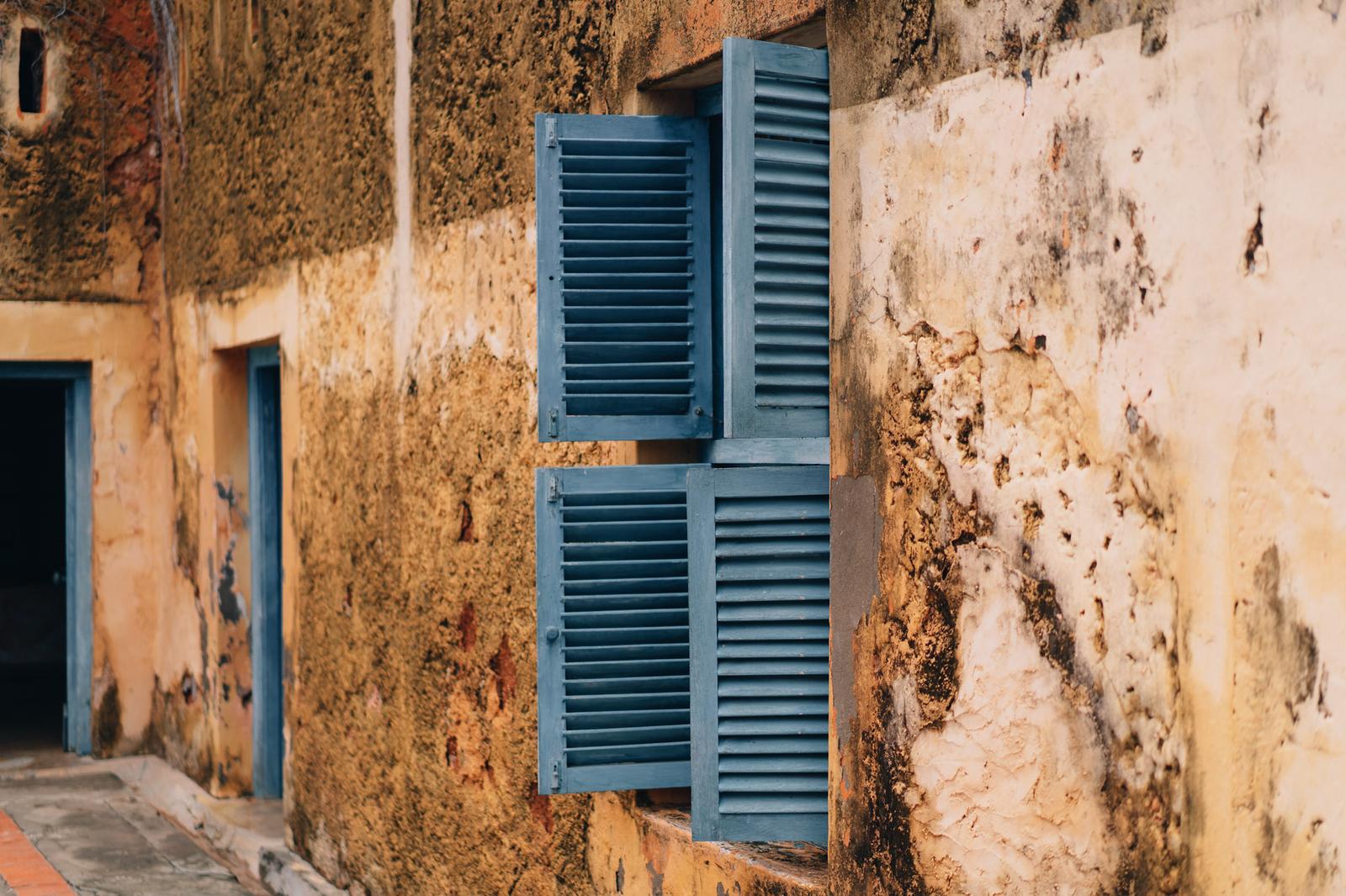Weathered blue wooden shutters on an old Stone Town building wall