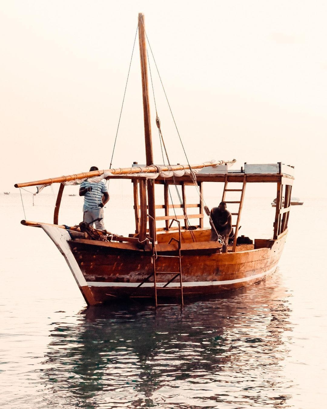 Wooden dhow on calm water in soft dawn light