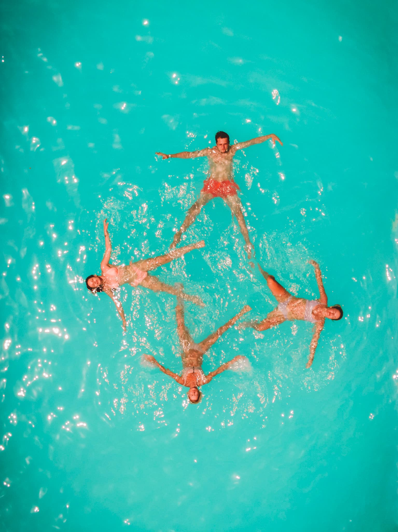 Aerial view of four travelers floating together in turquoise water